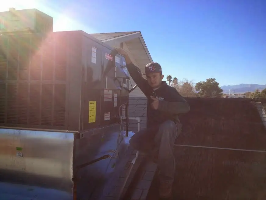 HVAC technician performing AC Tune-Up on a rooftop unit in Floresville